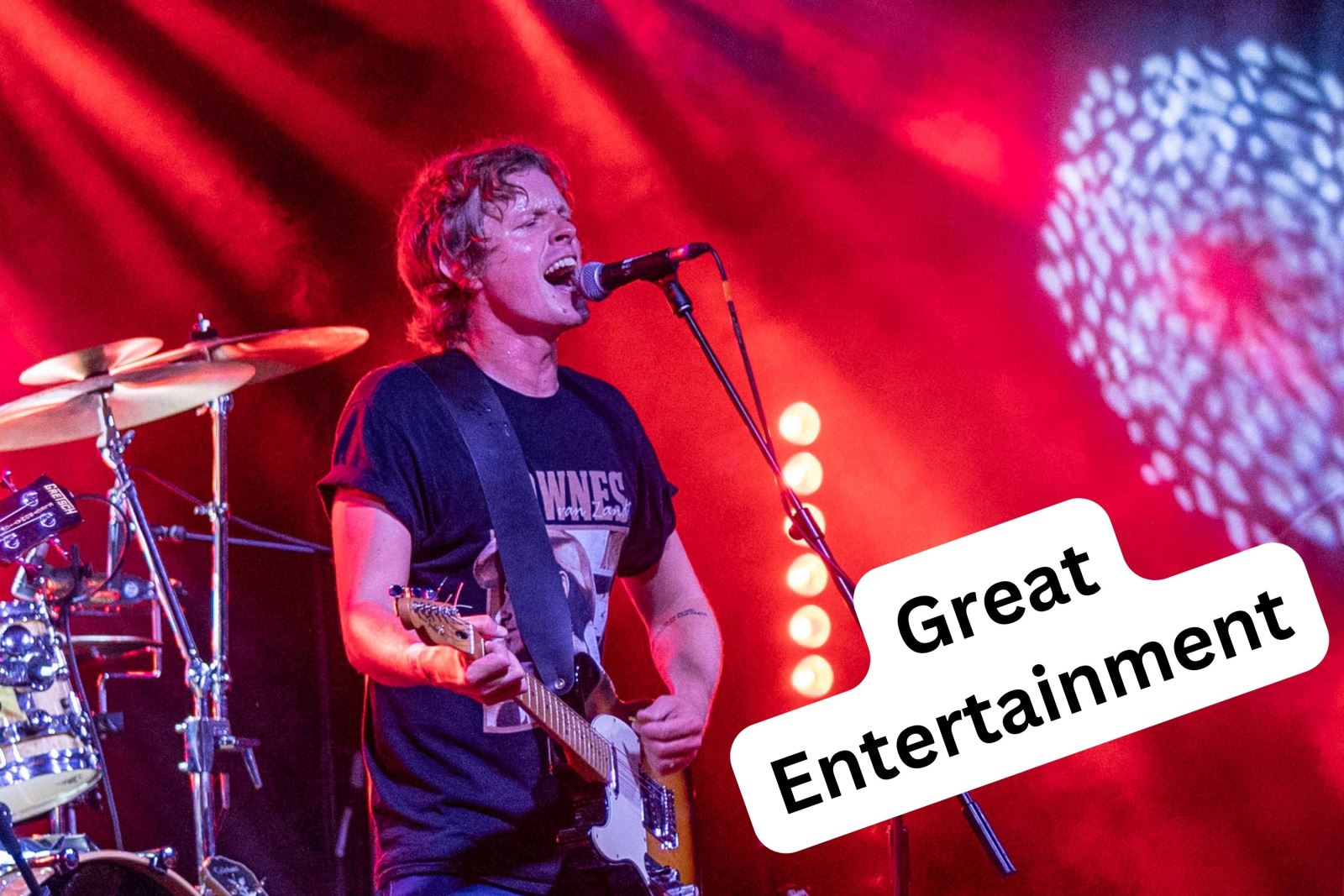 A guitarist singing into a microphone and stage lighting